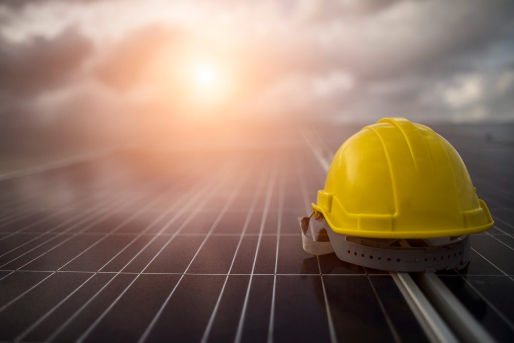 Elmetto giallo da lavoro su pannello fotovoltaico - Servizi e soluzioni energetiche Mariani
